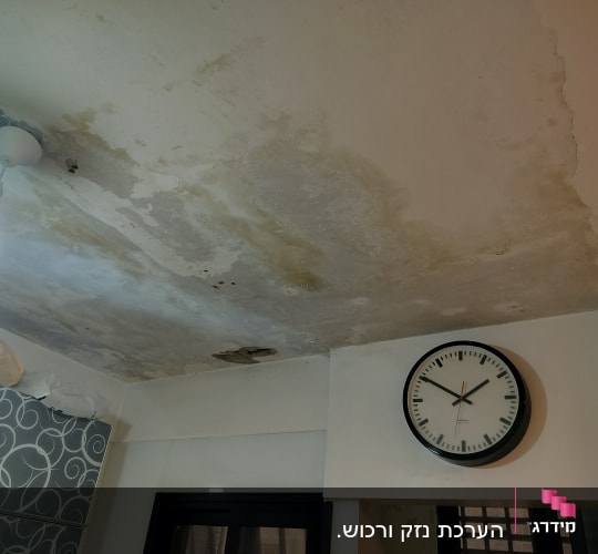 תקרה עם כתמי רטיבות ונזילות ליד מנורה ושעון קיר